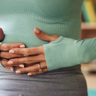 Woman holding her stomach to illustrate the connection between stress and gut health.