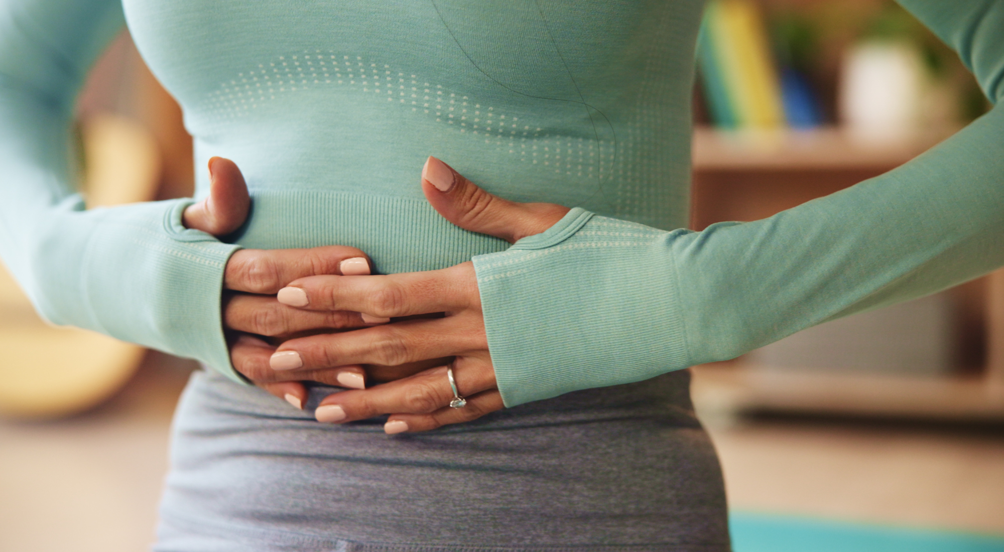 Woman holding her stomach to illustrate the connection between stress and gut health.